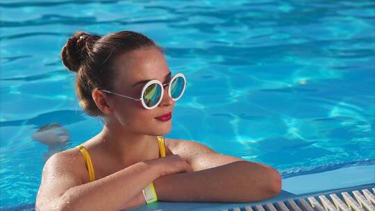 戴着太阳镜的年轻女子在游泳池里享受好天气晴天