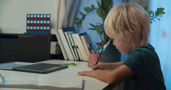 圣诞节假期坐在桌旁用铅笔画画的可爱儿童男孩