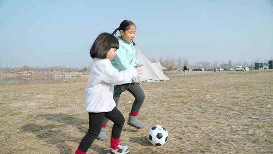 冬季在公园草坪上踢球的两个女孩