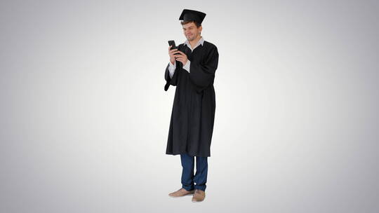 穿着毕业礼服的男学生在使用智能手机视频素材模板下载