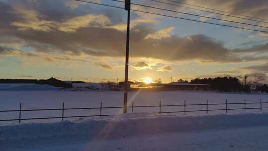 驱车驶过金色日落经过北海道深雪掩埋的农场