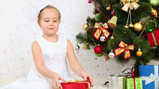 女孩坐在圣诞树抛洒五彩纸屑