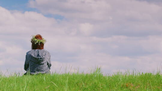一个孤独的女人坐在绿色的山上