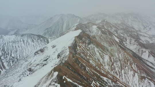 无人机飞越一侧积雪覆盖的山峰