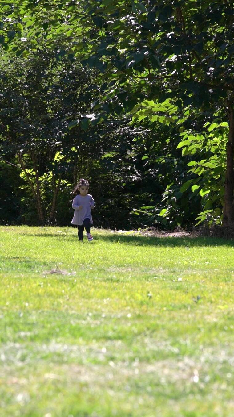 秋天午后站在草坪上玩耍的女孩实拍