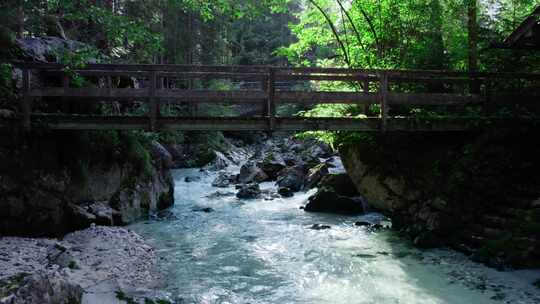 在木制小桥下沿着森林山溪急流空中飞行