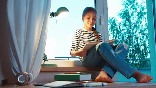学生坐在她房间的窗台上看书