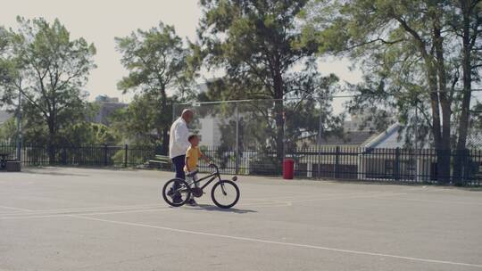 爸爸陪着孩子推着自行车