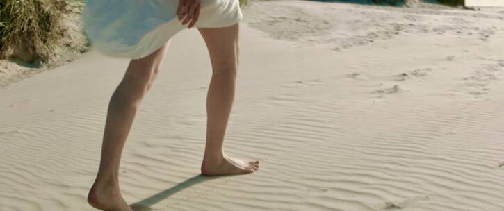 女孩光脚走在沙子上