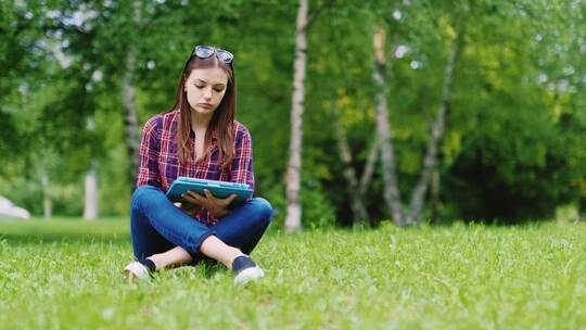 一名女学生正准备考试坐在公园的草坪上