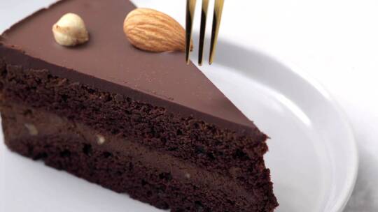用叉子把一块巧克力蛋糕放在黑色盘子里吃。