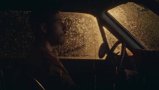 下雨天坐在车里吸烟的男人