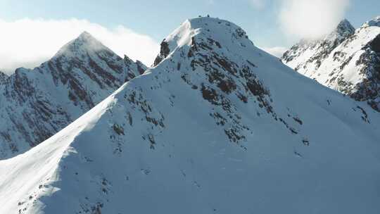 在滑雪板上沿着积雪覆盖的山脊攀登的人