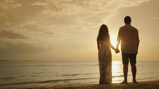 一对年轻夫妇正在欣赏海上日落 