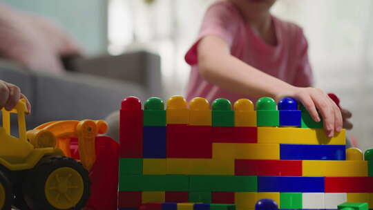 可爱的女孩用彩色塑料块建造结构
