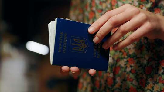 女性难民的手打开和关闭乌克兰护照，里面有许多旅行邮票