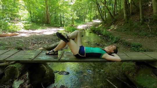 一个躺在木制小径上在森林里放松的女人