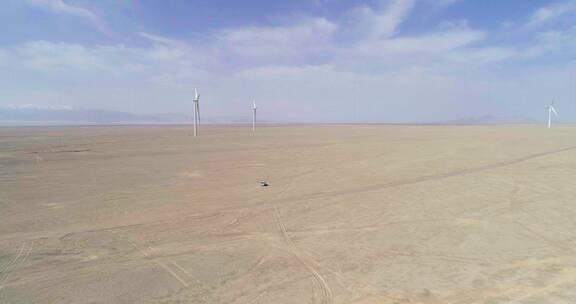 航拍行驶在戈壁滩风力发电基地的汽车