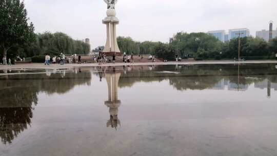 公园游人广场积水倒影