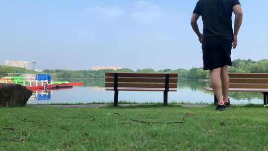 中年男子坐在湖边的长板凳上