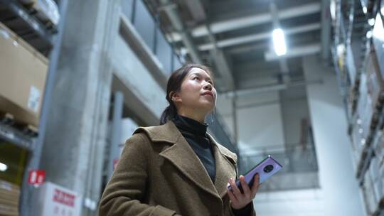 中年女性拿手机在超市仓库货架工厂仓储车间
