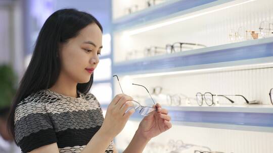 年轻女顾客在眼镜店选购眼镜