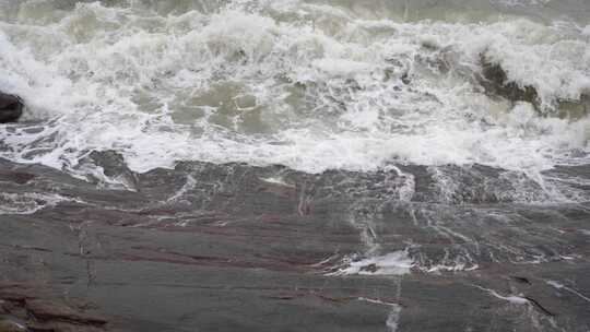 海浪拍打岩石浑浊海水冲刷礁石浪花阴天大海