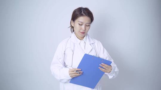 年轻女医生手持病历本书写记录
