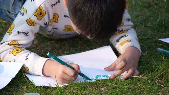 4K孩子在妈妈的陪同下在草坪上画画