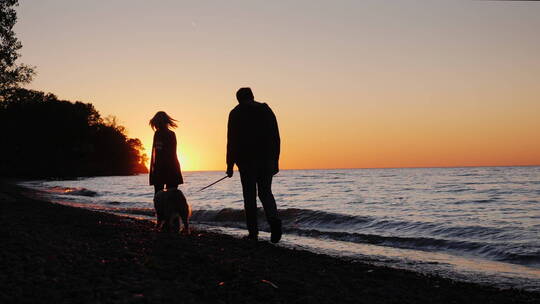 日落时在湖边遛狗的夫妇