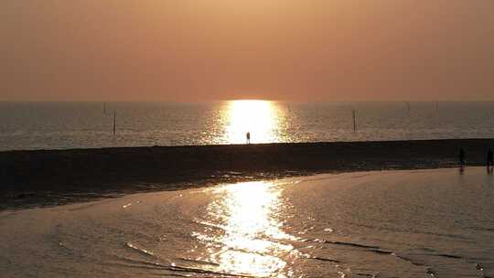 一个人走在夕阳照耀下的沙滩上