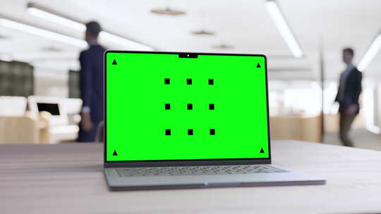 办公桌上带绿屏的笔记本电脑
