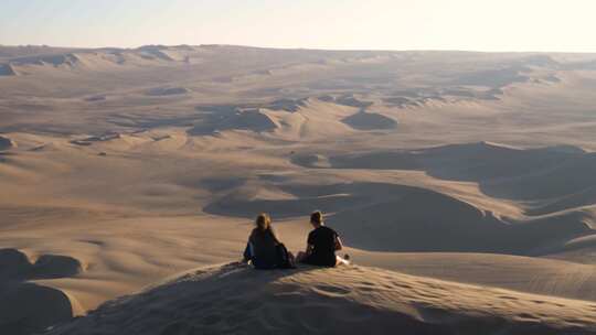 两个年轻人坐在沙丘上