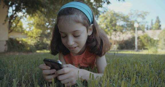 女孩趴在草地上玩手机