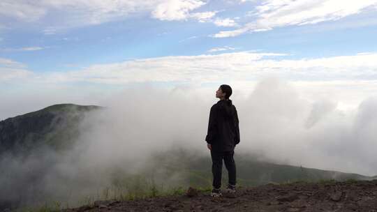 女性青年站在山顶看风景背影看远山感受自然