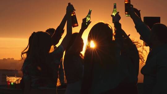 一群朋友在屋顶上喝啤酒夕阳剪影