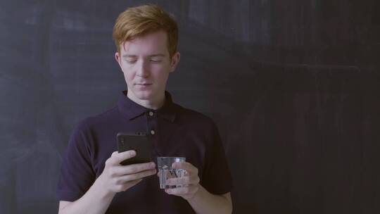 男人端着水杯玩手机视频素材模板下载