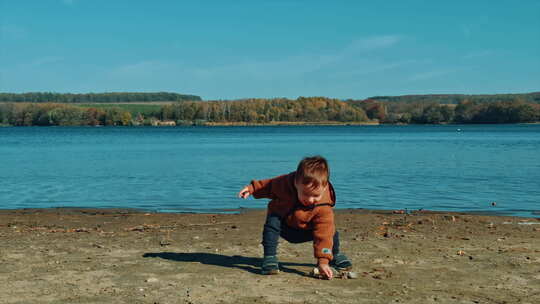 兴奋的蹒跚学步的孩子向河里扔石头。秋天，
