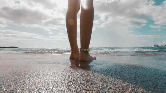 女生站在沙滩上，海浪冲向脚上
