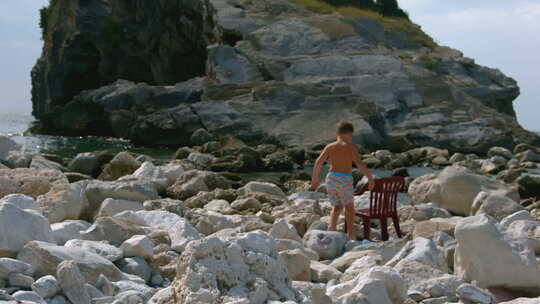 男孩坐在海边的椅子上