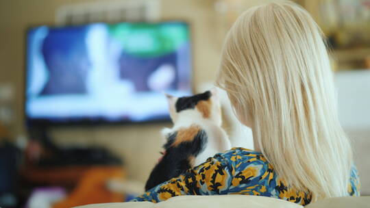 女人抱着猫看电视视频素材模板下载
