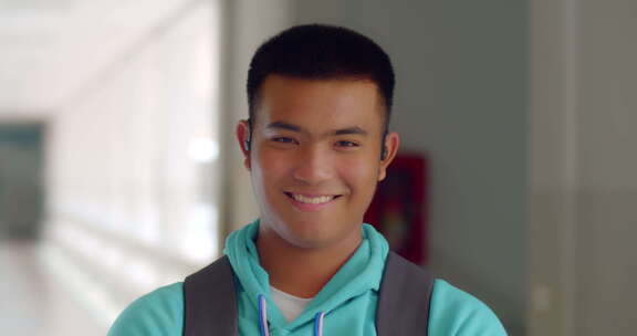 一个快乐微笑的男高中生站在走廊上