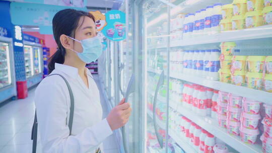戴口罩的青年女人在超市挑选酸奶视频素材模板下载