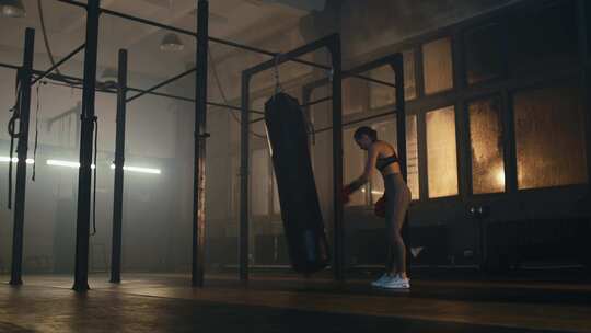 拳击手在昏暗的健身房打拳击沙袋视频素材模板下载