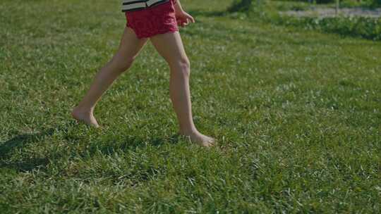 小女婴赤脚走在绿色草地上的夏季特写慢动作视频素材模板下载