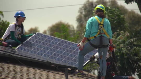 工人们在屋顶上安装太阳能电池板
