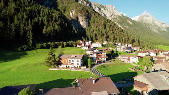 日落阿尔卑斯山绿色山谷中奥地利村庄的鸟瞰图
