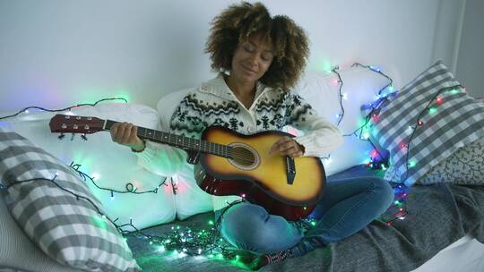 坐在围着彩灯的沙发弹吉他