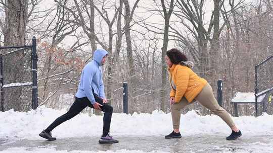 男人和女人在雪地公园做弓步