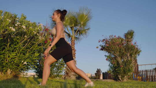 健康女运动员在阳光下户外弓步运动的侧视图宽镜头